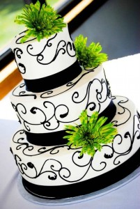 white wedding cake with dark swirls and green accents